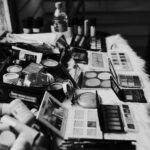 Black and white high angle of assorted makeup products and tools placed on dressing table near mirror