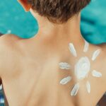 Sun Drawing Sunscreen on Child s Back Photo